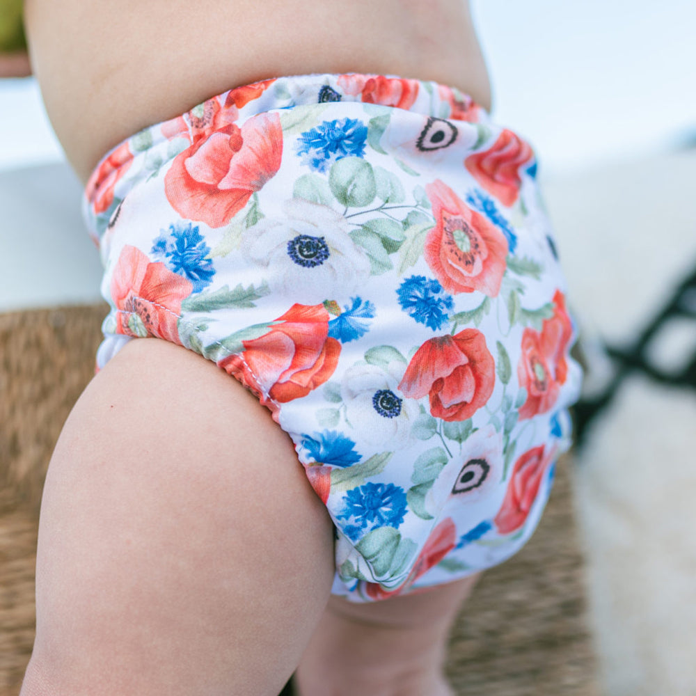 Nahaufnahme: Baby in der Doodush Überhose V2.0 mit Laschen im Design Field Poppies (Feldblumen)