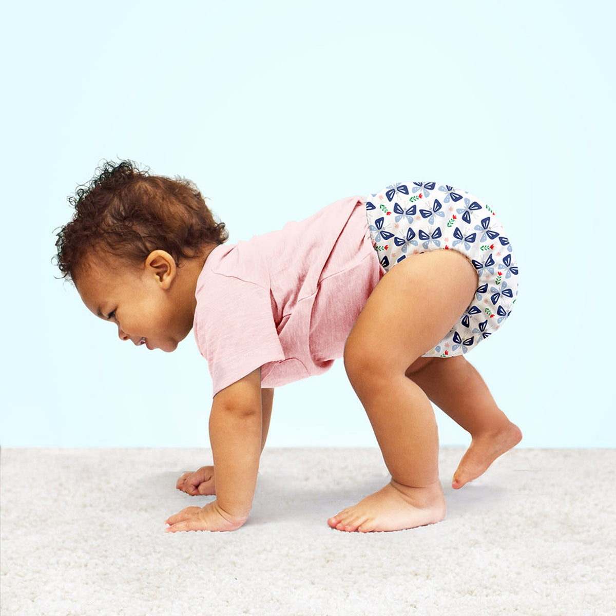 Krabbelndes Kind in einer Bambino Mio Windel im Design Butterfly Bloom
