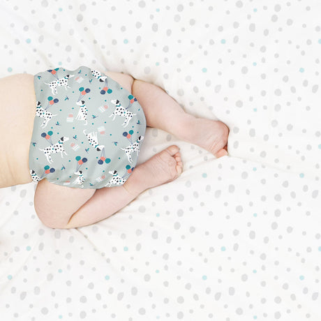 Baby liegt in einer Bambino Mio Windel im Design Puppy Party