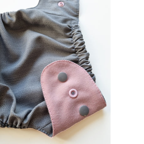 Detail der Doodush Wollüberhose Magnolia mit rosa Druckknopf-Lasche