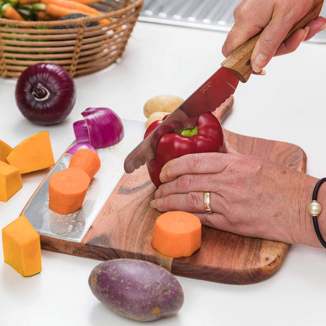 KiddiKutter KandoKutter in Gebrauch: Erwachsene Hände schneiden rote Paprika auf dem Holzbrett