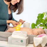 Mutter wickelt ihr Baby am Wickeltisch, daneben die Popolini Popli Windelvlies-Box