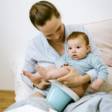Mutter hält ihr Baby zum Abhalten über ein Töpfchen mit Popolini Töpfchenbezug